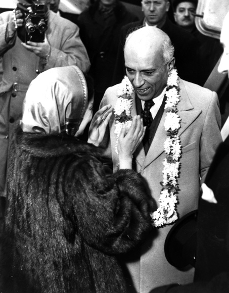 Jawaharlal Nehru being presented with a garland of flowers by the wife of the Indian ambassador in Paris on his arrival at Le Bourget airport.