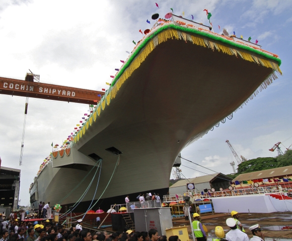 Employees of Cochin shipyard stand beside India's indigenous aircraft carrier P-71 Vikrant built for the Indian Navy during its launch in Kochi