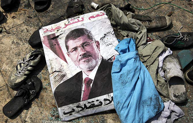 A poster of deposed Egyptian President Mohamed Mursi that reads 'Yes to legitimacy; no to the coup' lies amid the debris of a cleared protest camp