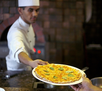 A chef passes a pizza to a waiter inside the kitchen of a hotel in Amritsar. Photo credit: Yasir Iqbal/Reuters 