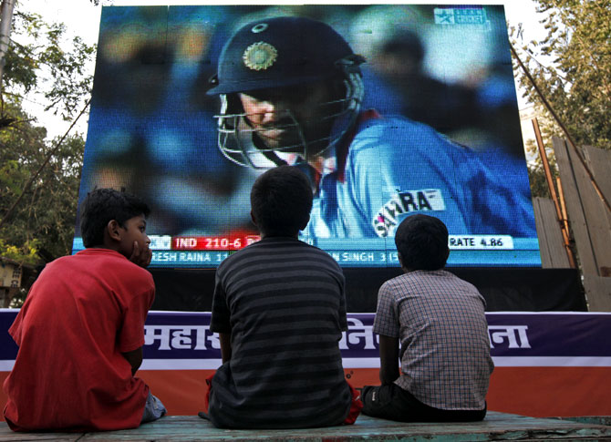 Children watch a cricket match on a big screen in Mumbai