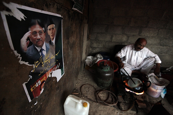 A poster of former Pervez Musharraf, with Muhammad Ali Jinnah, founder and first governor-general of Pakistan, is pictured on a wall as a man prepares snacks in Islamabad