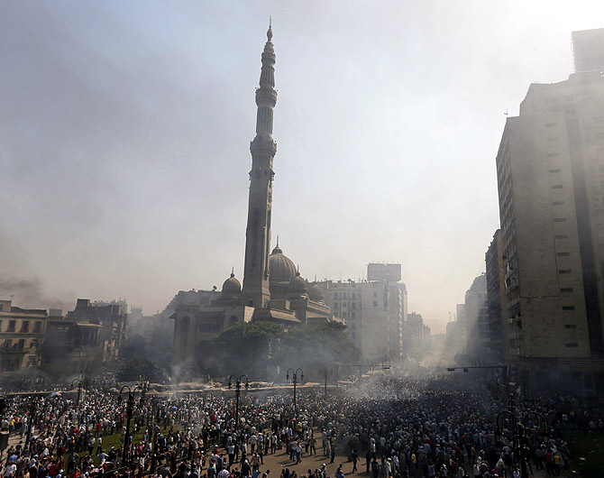 Members of the Muslim Brotherhood and supporters of ousted Egyptian President Mohamed Mursi flee from shooting in front of Azbkya police station during clashes at Ramses Square in Cairo