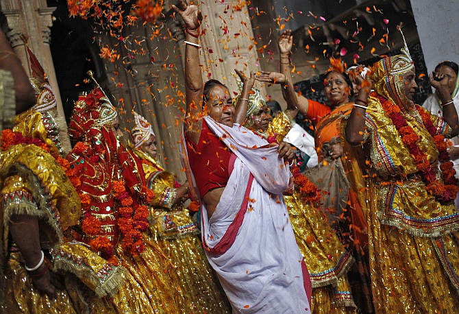 A woman throws flower petals and dances with widows dressed as Radha, during celebrations to mark Janmashtami festival at the Meera Sahavagini ashram in Vrindavan in Uttar Pradesh