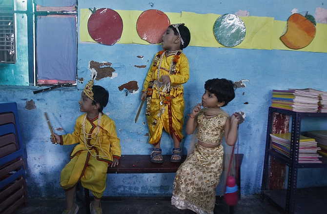 Boys dressed as Krishna and a schoolgirl wait for their performance to start inside a classroom during the celebrations to mark Janmashtami in New Delhi.