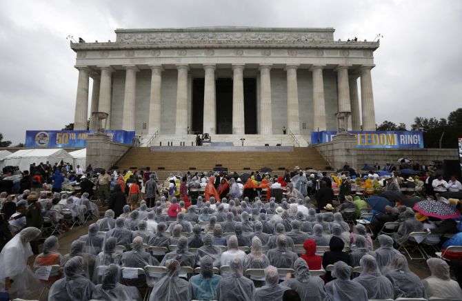 Attendees wear rain coats during a storm at a ceremony marking the 50th anniversary of Martin Luther King Junior's I have a dream speech on the steps of the Lincoln Memorial in Washington