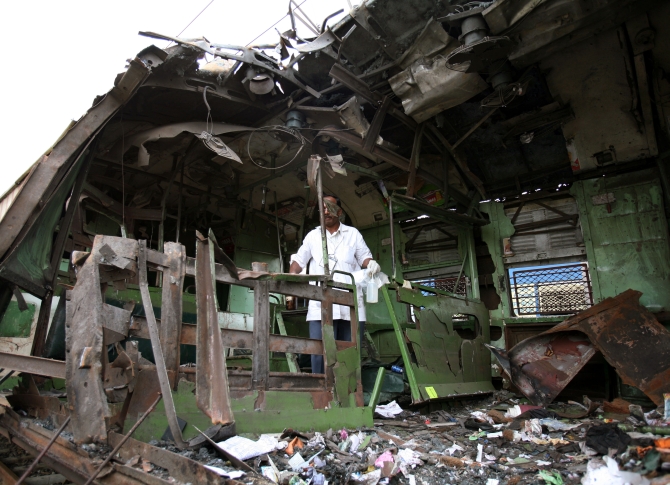 A forensic officer examines a damaged railway train compartment hit by serial blasts in Mumbai in July 2006