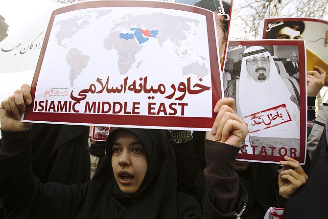 Women protesters hold a placard and a poster of Saudi Arabia's King Abdullah during a protest