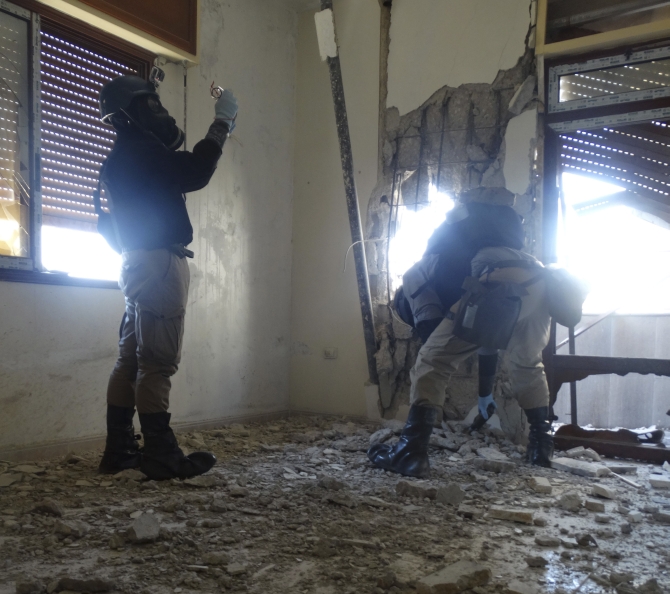 UN chemical weapons experts, wearing gas masks, inspect one of the sites of an alleged chemical weapons attack in the Damascus' suburb of Zamalka