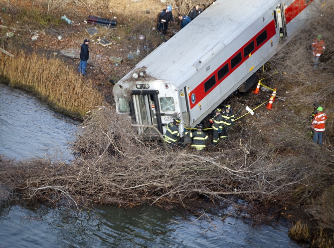 Emergency workers examine the site of a Metro-North train derailment in the Bronx borough of New York