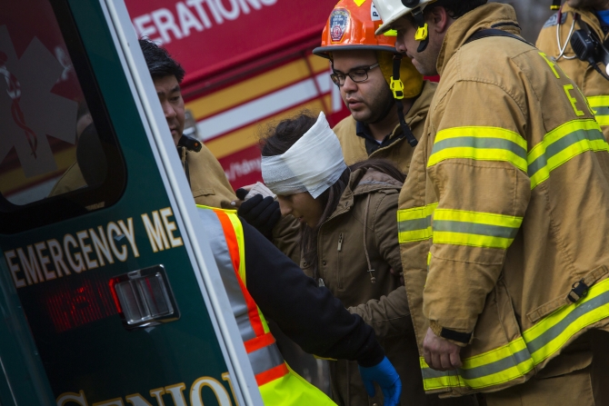 A woman is taken to an ambulance at the site of a Metro-North train derailment in the Bronx borough of New York