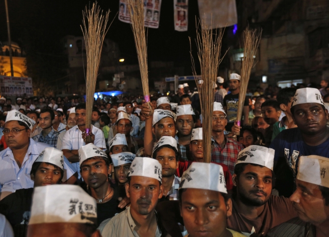 AAP supporters hold brooms, the party's symbol, during a public meeting in New Delhi