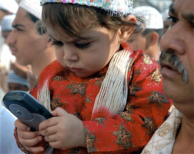 A child plays with a mobile phone during a festival
