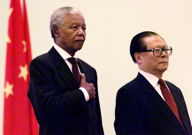 South African President Nelson Mandela escorted by the then Chinese President Jiang Zemin listens to the South African national anthem during a welcoming ceremony at the Great Hall of the People in Beijing in May 1999