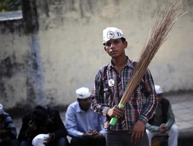 A supporter of the Aam Aadmi Party holds a broom, the party's symbol, during a rally