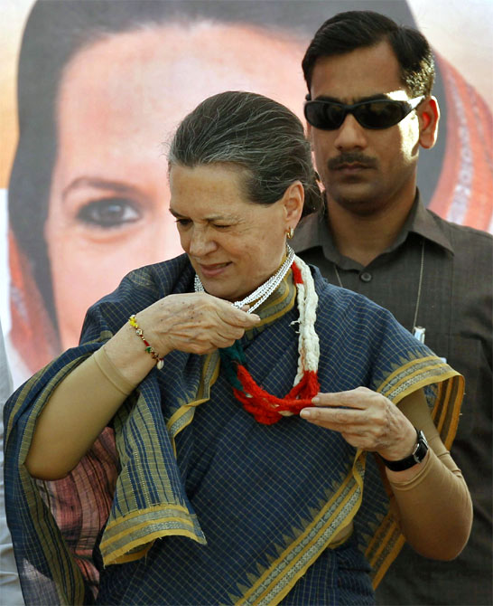 Congress President Sonia Gandhi tries to take off a garland presented to her by a supporter as she arrives to address a rally ahead of the state elections in Dungarpur, Rajasthan