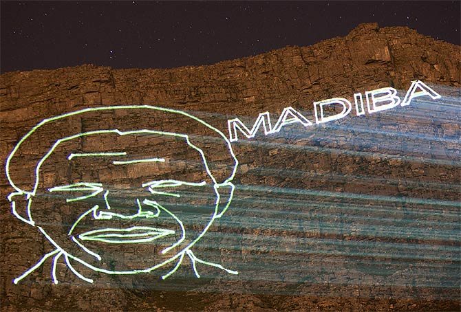 A projection of the face of former South African President Nelson Mandela and his clan name Madiba is projected onto the face of Table Mountain in Cape Town