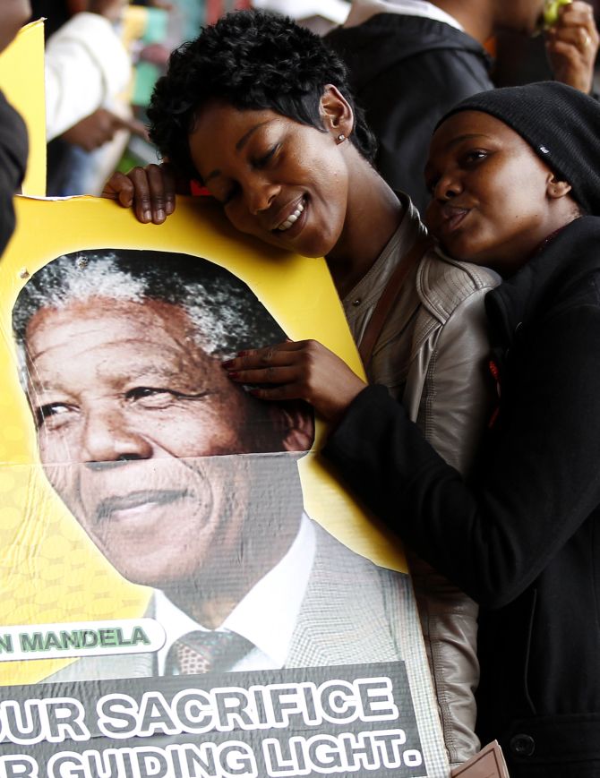 People pose for a picture while holding a placard during the national memorial service for former South African President Nelson Mandela at the First National Bank (FNB) Stadium, also known as Soccer City, in Johannesburg 