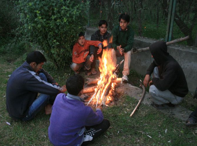 Kashmiri boys warm themselves around a fire during a cold day in Srinagar
