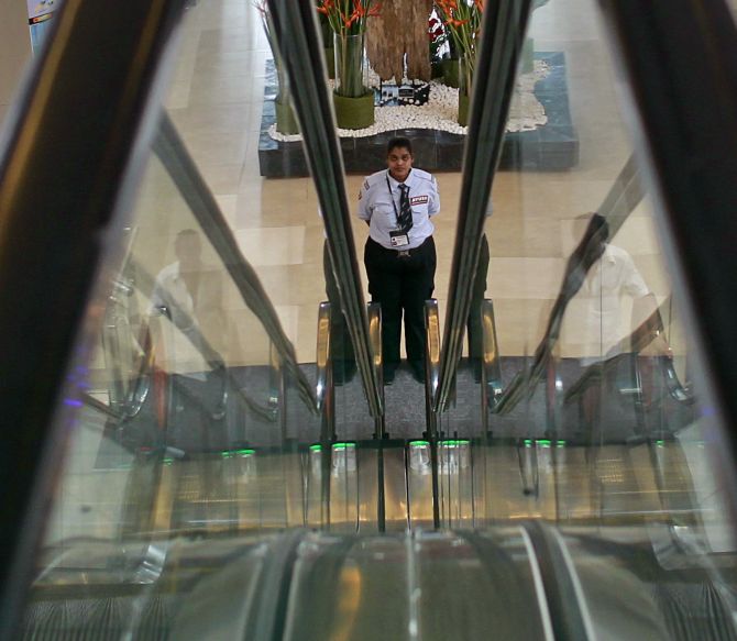 A female private security personnel stands guard between escalators inside a shopping mall in Mumbai.
