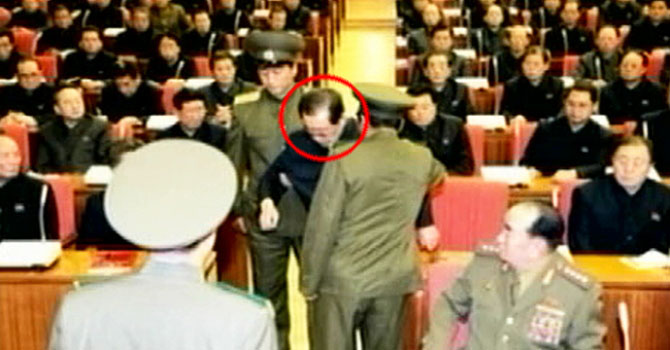 Jang (circled) being dragged from a meeting by the police in Pyongyang as other members look on.