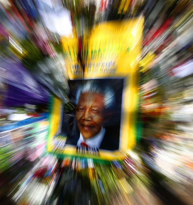 A poster depicting a photo of former South African President Nelson Mandela is seen among flowers outside of Mandela's house in Johannesburg