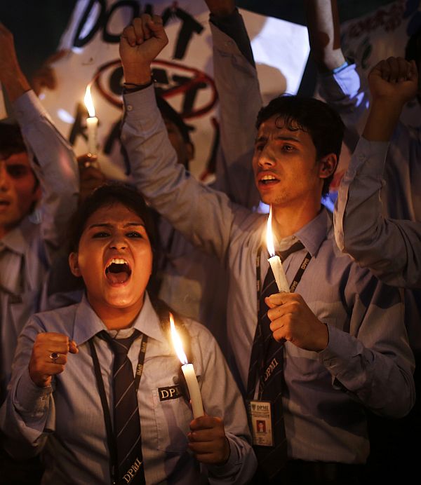 School children shout slogans as they hold candles during a candle light vigil to mark the first anniversary of the Delhi gang rape