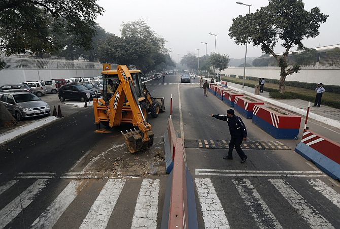 A traffic policeman guides a bulldozer removing the security barriers in front of the US embassy in New Delhi