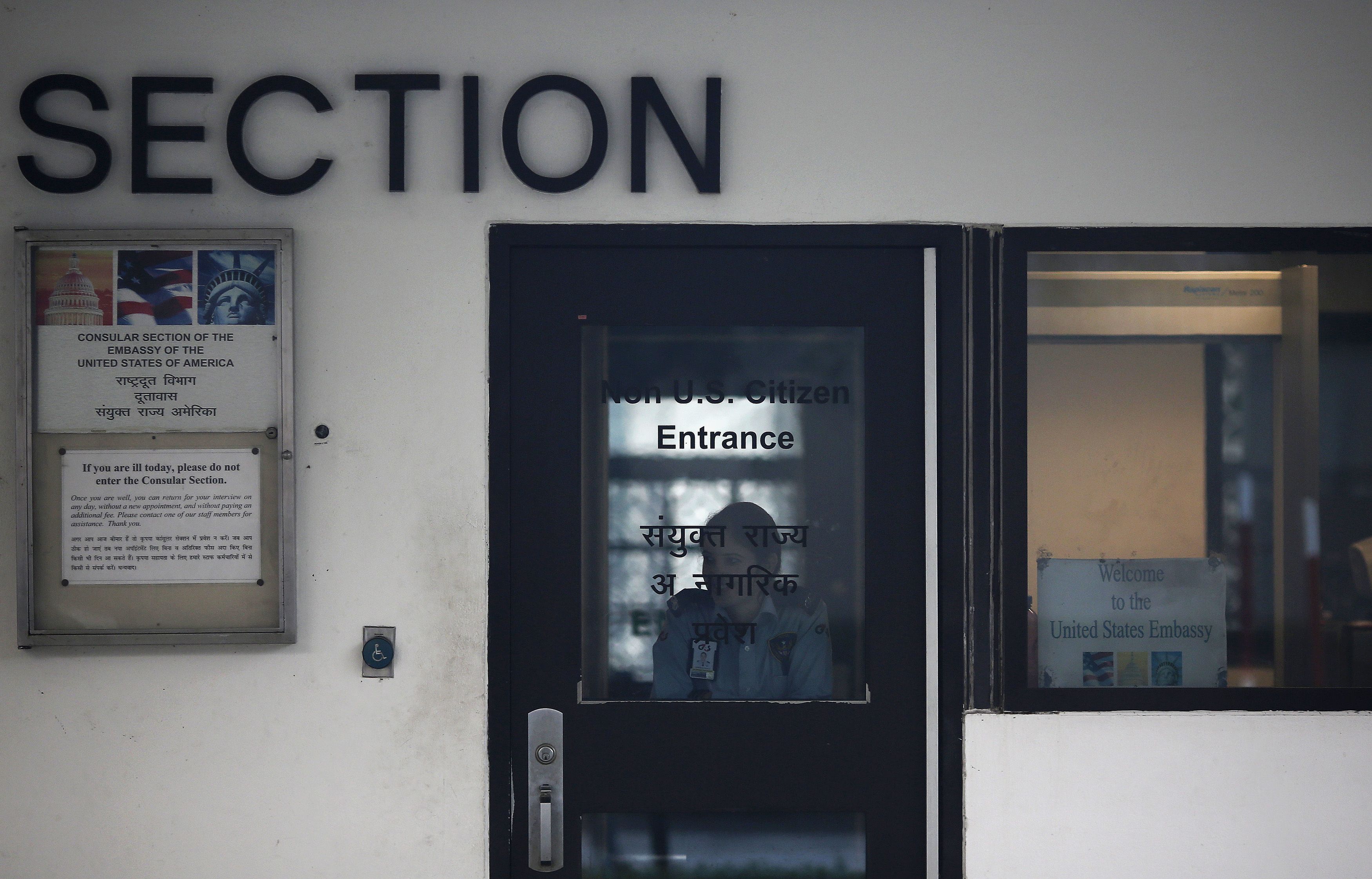 A US embassy employee looks out from a door as she watches a bulldozer removing the security barriers