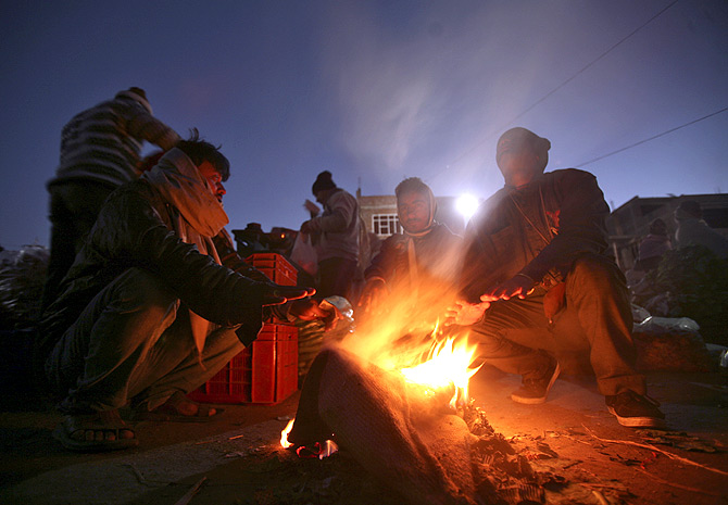 People warm themselves around a fire at a vegetable wholesale market in Jammu.