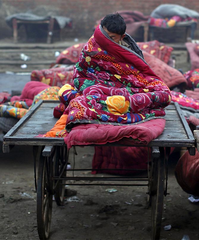 A migrant labourer sits under a quilt in the old quarters of Delhi