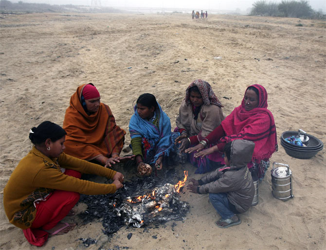 Women warm themselves by a fire in Jammu