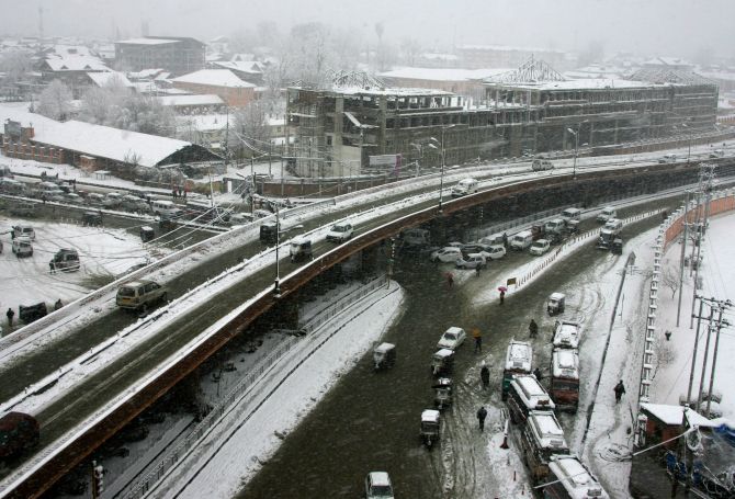 Vehicles move sluggishly during heavy snowfall in Srinagar on Tuesday