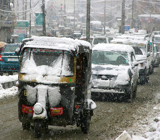 Vehicles move slowly during heavy snowfall in Srinagar on Tuesday