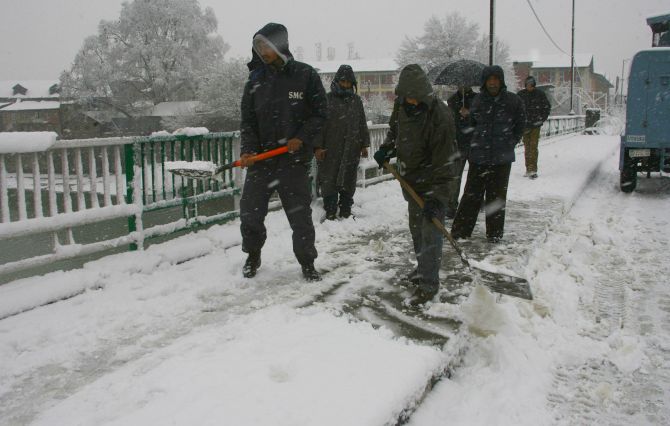 Srinagar Municipal Corporation workers clear snow on the roads on Tuesday