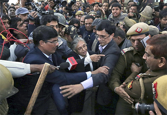 -Delhi's Chief Minister Sheila Dixit (C) is escorted by security personnel after she was blocked by demonstrators while entering the venue for the protests in New Delhi
