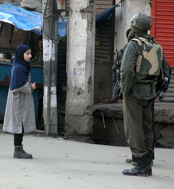A Kashmiri girl seeks permission from security personal to access a cordoned off street