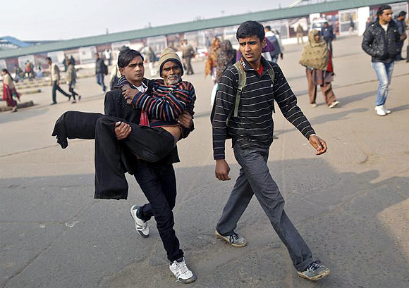 A man carries his sick father in his arms as no public transport was available outside Delhi railway station