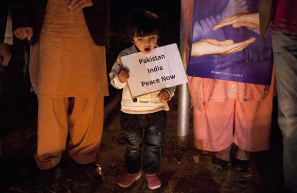 A girl holds a placard while observing a global vigil for peace between India and Pakistan