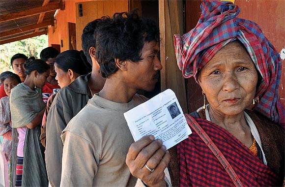 A woman shows her election card as she stands in a queue to vote