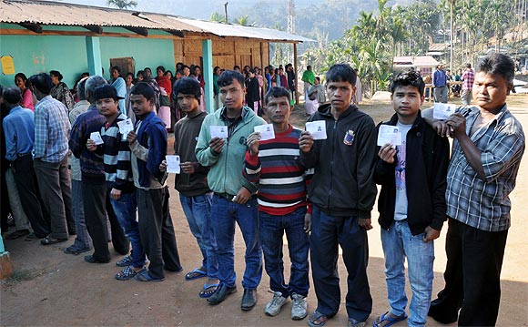 Youths display their identity card outside a poll booth