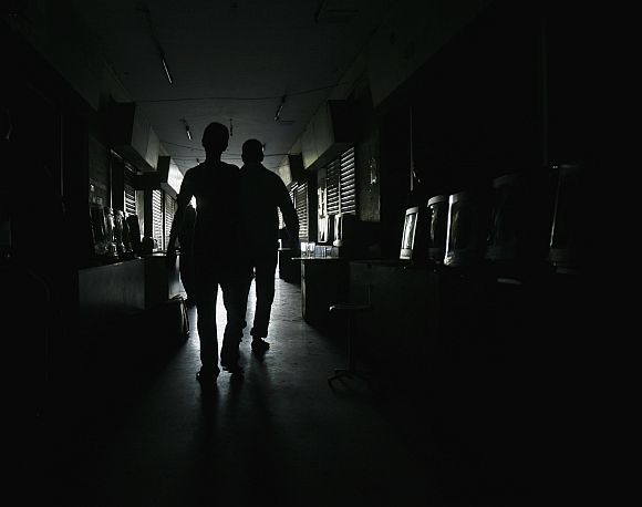 Men are silhouetted while they walking through a computer market during a power outage in Karachi