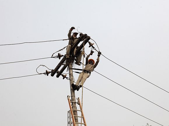 Technicians work on power lines supplying electricity in Lahore