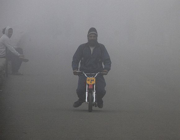 A man rides his mini bike amid dense fog on a cold winter morning in Chandigarh
