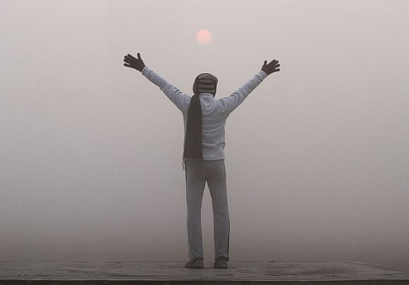A man exercises as the sun rises amid dense fog on a cold winter morning