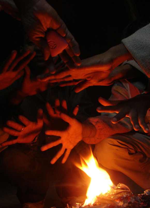 People warm their hands by a fire on a cold day in Allahabad, Uttar Pradesh