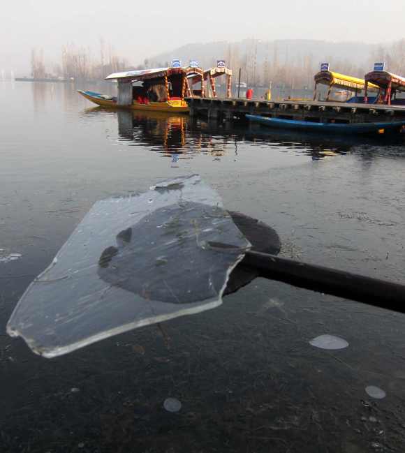 A boatman picks up ice formed on the Dal Lake with the help of his oar