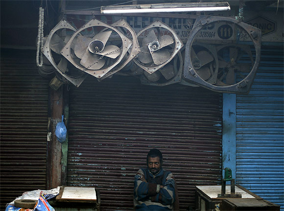 A man sits in front of closed shops at a market