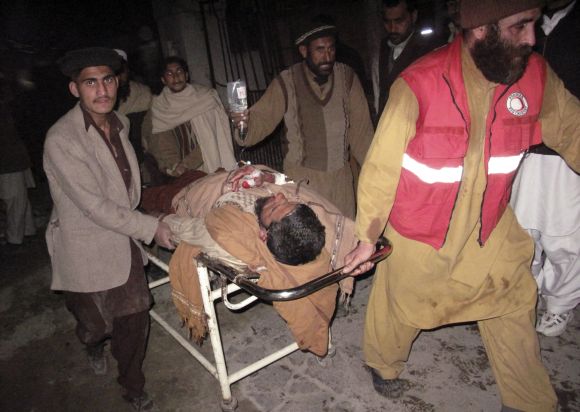 Rescue personnel wheel an injured man from the scene of a bomb explosion at Maki mosque in Takhtaband, on the outskirts of Mingora