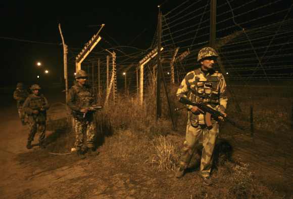Border Security Force soldiers walk during night patrol near the fenced border with Pakistan in Abdullian, southwest of Jammu